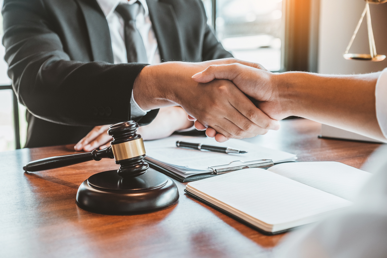 Lawyer and client shaking hands over a wooden table with legal documents and a gavel, symbolizing legal representation and plea negotiations in DUI cases.